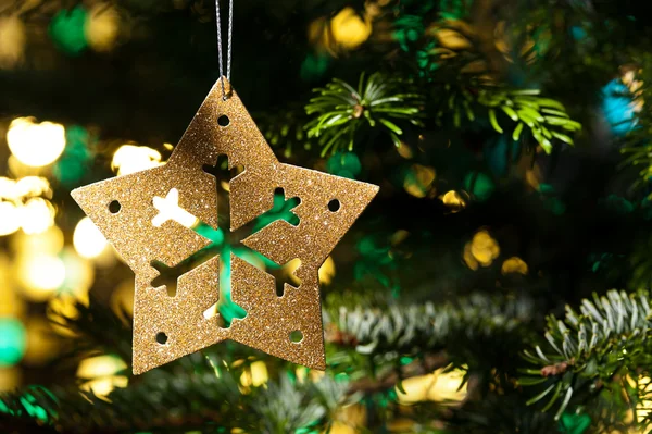 Dekorativní Zlatá hvězda ornament v vánoční stromeček — Stock fotografie
