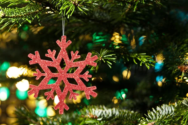 Red artificial snow flake in a christmas tree — Stock Photo, Image