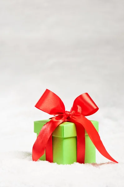 Grünes Geschenk mit rotem Band über Schnee — Stockfoto