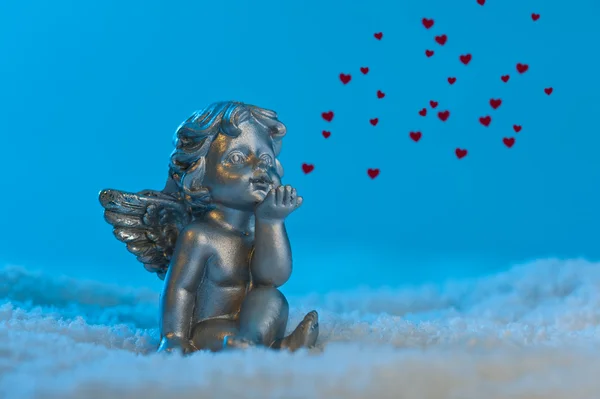 Angel in a beautiful blue snow setting, shows heart — Stock Photo, Image
