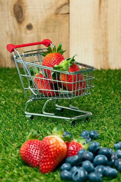 Strawberries in a shopping cart in front of a timber wall — Stock Photo, Image