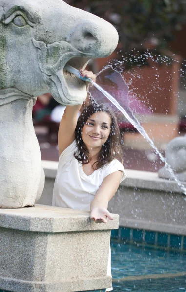 Beautiful young woman is playing with fountain — Stock Photo, Image