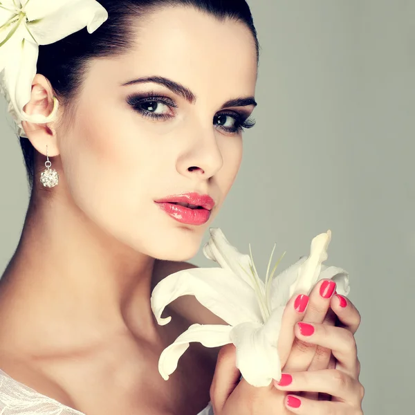 Elegante sexuelle Brünette in einem Brautkleid mit Lilien im Haar — Stockfoto
