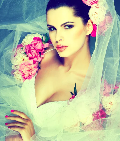 Una elegante morena sexual está en un vestido de novia, decorado con colores rosados —  Fotos de Stock