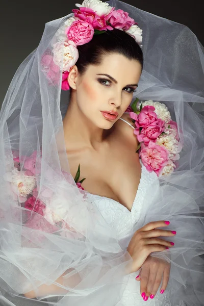 Un'elegante bruna sessuale indossa un abito da sposa, decorato con colori rosa Immagine Stock