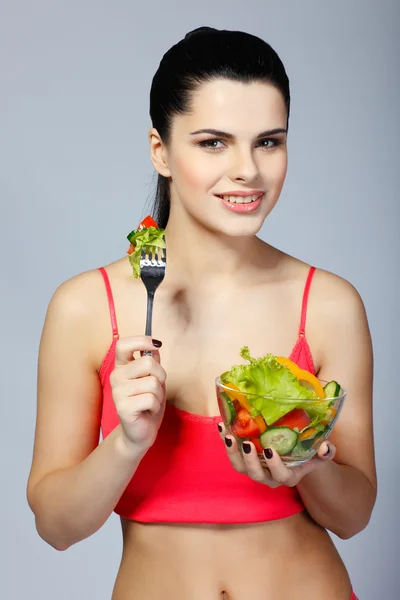 Ritratto di una bella giovane donna che mangia insalata di verdure isolata su sfondo bianco — Foto Stock