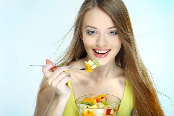 Porträtt av en ganska ung kvinna äta fruktsallad isolerad på en vit bakgrund — Stockfoto