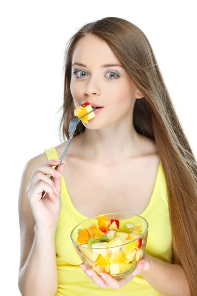 Porträtt av en ganska ung kvinna äta fruktsallad isolerad på en vit bakgrund — Stockfoto