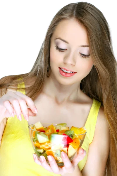Retrato de una hermosa joven comiendo ensalada de frutas aislada sobre un fondo blanco — Foto de Stock