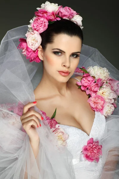 Una elegante morena sexual está en un vestido de novia, decorado con colores rosados —  Fotos de Stock