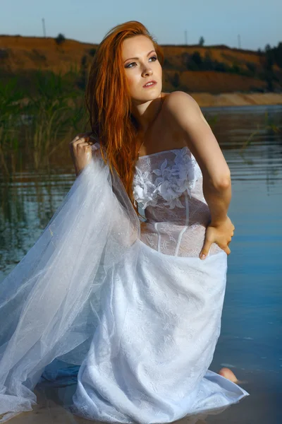 stock image Beautiful redheaded woman in a wedding-dress in water