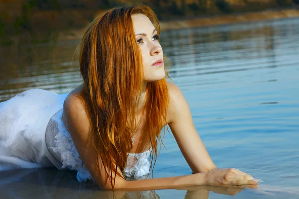 Bella donna dai capelli rossi in un abito da sposa in acqua — Foto Stock