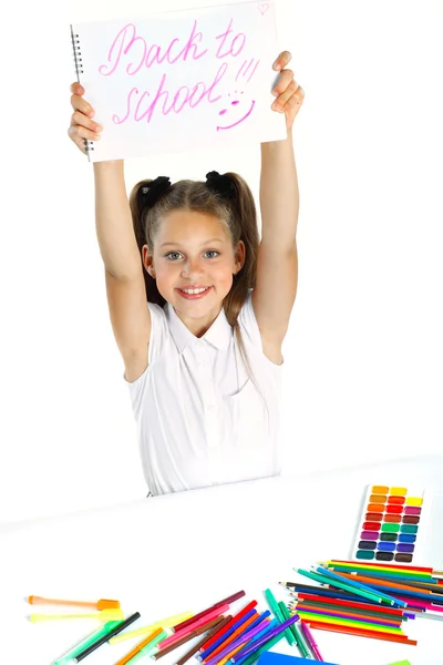 Ein schönes Mädchen in Schulform, das einen Filzstift zeichnet, isoliert auf weißem Hintergrund — Stockfoto