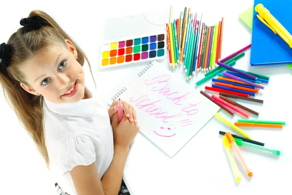 Uma menina bonita em forma de escola desenhando um marcador, isolado em um fundo branco — Fotografia de Stock