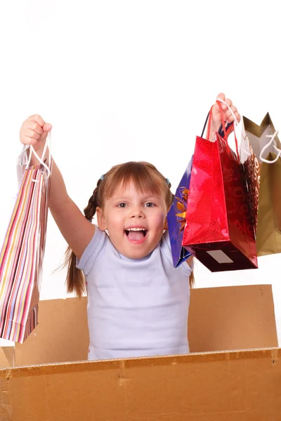Happy little girl in a cardboard box with purchases — Stock Photo, Image
