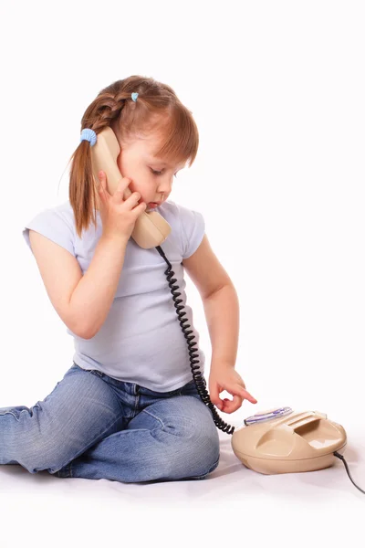 Söt liten tjej ringer upp numret på den gamla telefonen — Stockfoto