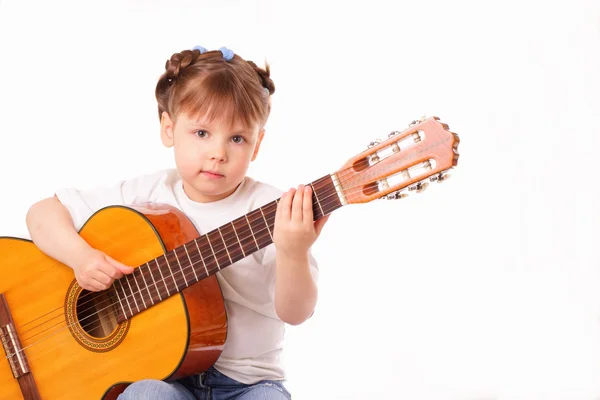 Маленькая девочка играет на старой концертной гитаре — стоковое фото