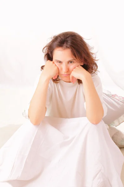 Arg ung kvinna sitter i sängen — Stockfoto