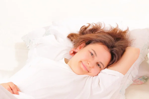 Çekici bir genç kadın yatakta rahatlatıcı — Stok fotoğraf
