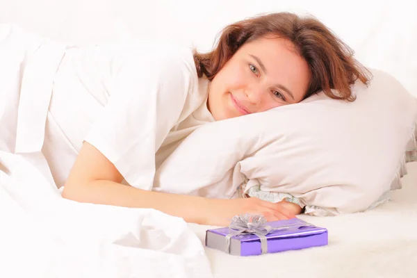 Mooie jonge vrouw ontspannen in bed met een souvenir — Stockfoto