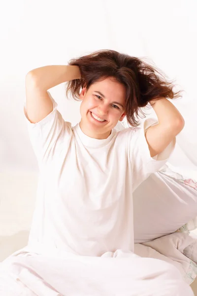 Mujer joven divertida sentada en la cama —  Fotos de Stock
