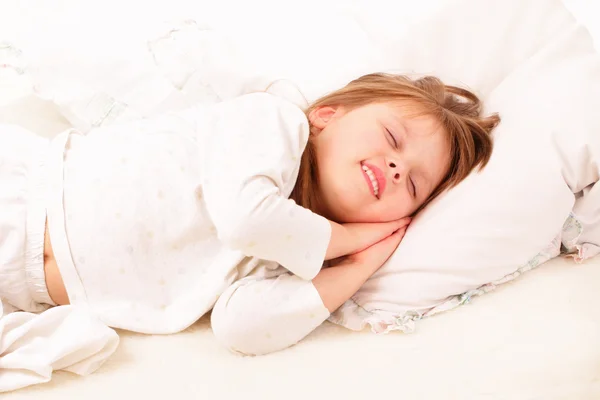 Glückliches kleines Mädchen schläft im Bett — Stockfoto