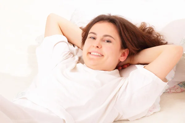 快乐的年轻女人放松躺在床上 — 图库照片