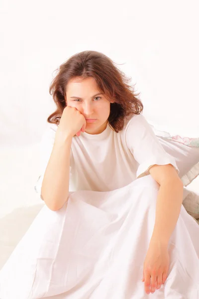 Серйозна молода жінка сидить у ліжку — стокове фото