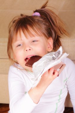 Pretty little girl eating chocolate clipart