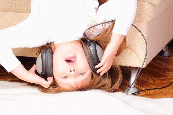 Beautiful little girl upside down with headphones — Stock Photo, Image