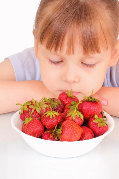 Vacker liten flicka och en vit soppa tallrik med jordgubbar — Stockfoto