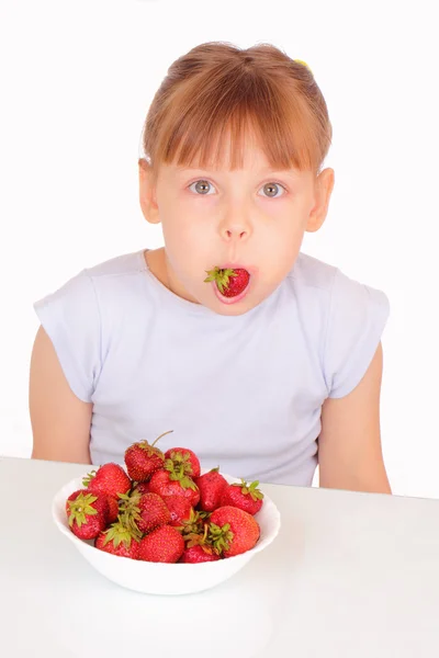 딸기를 먹는 재미 있는 어린 소녀 스톡 사진