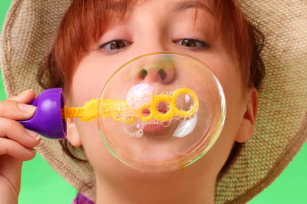 Careless young girl in a hat blowing soap bubbles — Stock Photo, Image