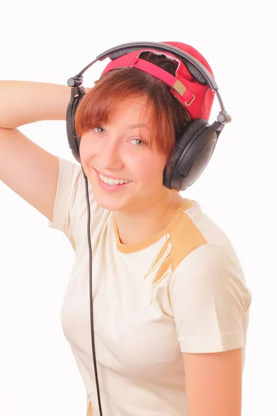 S úsměvem mladá dívka poslouchá hudbu se sluchátky — Stock fotografie