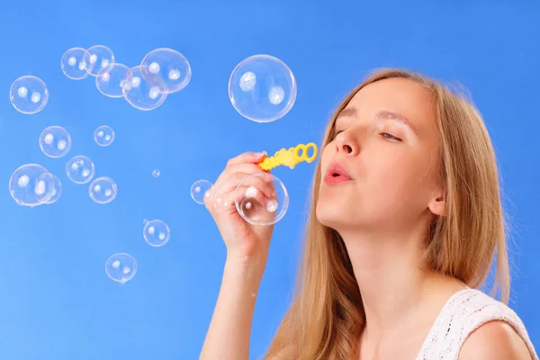 Schöne junge Frau pustet Seifenblasen — Stockfoto