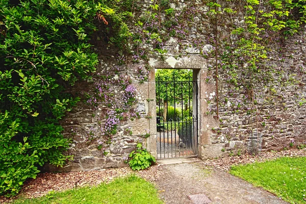 Vieux mur de jardin en pierre avec portail métallique — Photo