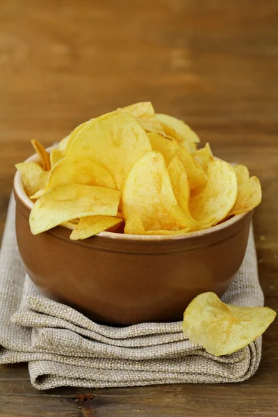 Potato chips in ceramic bowl on a wooden table — Stock Photo, Image