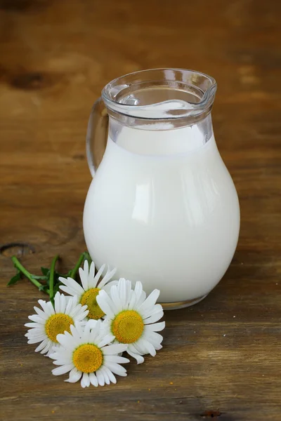 Milchkrug auf Holztisch wünscht Gänseblümchen, rustikales Stillleben — Stockfoto