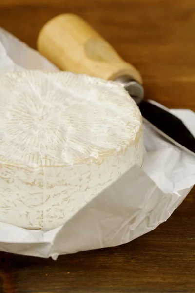 Camembert de queso sobre una mesa de madera y un cuchillo especial —  Fotos de Stock