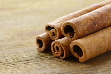 Cinnamon sticks on wooden background clipart