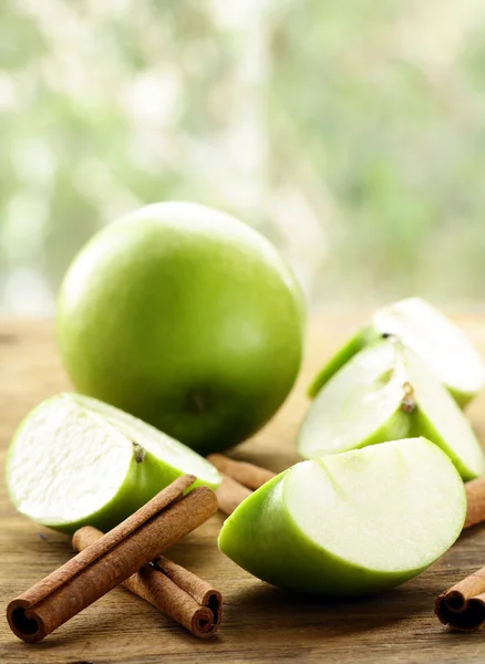 Зелені яблука та палички кориці на дерев'яному фоні — стокове фото