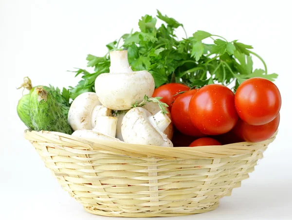 Mushrooms, cucumbers, tomatoes and herbs in a basket — Stock Photo, Image