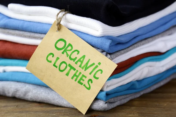 Стопка разноцветной одежды с органической этикеткой — стоковое фото