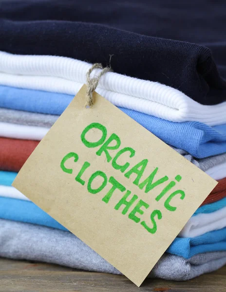 Стопка разноцветной одежды с органической этикеткой — стоковое фото