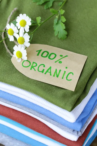 Pilha de roupas coloridas com etiqueta orgânica — Fotografia de Stock