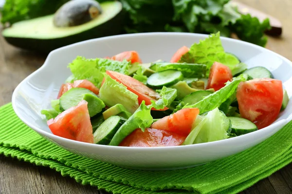 Verse salade met avocado en tomaat op een houten tafel — Stockfoto
