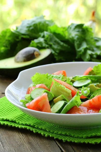 Čerstvý salát s avokádem a rajče na dřevěný stůl — Stock fotografie