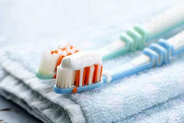 Un par de cepillos de dientes con pasta de dientes en una toalla — Foto de Stock