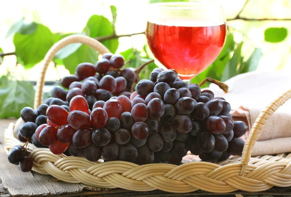 Escova de uvas orgânicas pretas com folhas na mesa de madeira — Fotografia de Stock