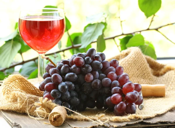 Кисть из черного органического винограда с листьями на деревянном столе — стоковое фото